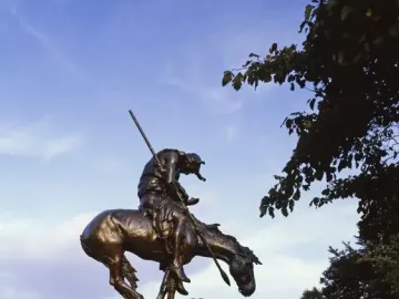 End of the Trail bronze statue of a bowed rider on a horse atop a stone pedestal.