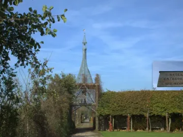 The Green Cathedral vine-covered archway with a path leading through it beside a dense hedge and benches.