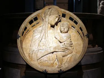 Madonna del Perdono relief showing the Madonna holding the child on her lap within a circular frame.