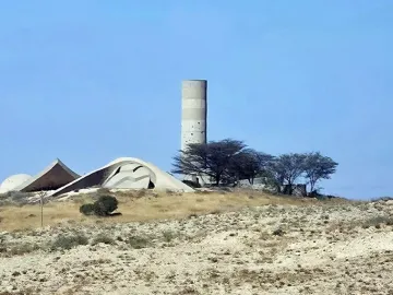 The Monument to the Negev Brigade, with a tall cylindrical concrete tower and sculptural low concrete forms on a barren hill.