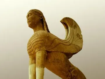 The Sphinx of Naxos stone sculpture with a woman\'s head, feathered wings, and a lion-like body on a decorative base.