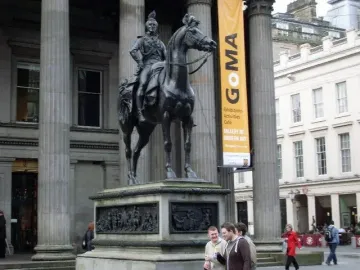 Duke of Wellington statue on a stone pedestal, with smaller figures at the base in a park setting.