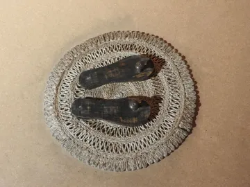 Paduka wooden sandals displayed on a woven mat.