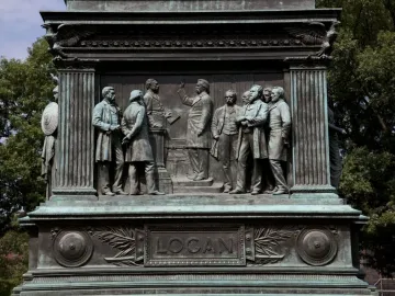 Bronze base of the Major General John A. Logan monument with a relief of several men and a plaque reading Logan.