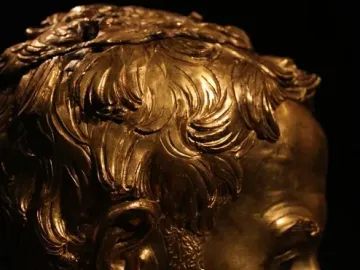 Saint Rossore Reliquary gilded bust in profile, showing curly hair, beard, and mustache.
