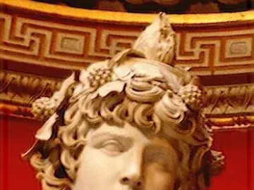 Upper portion of the Antinous Braschi marble sculpture, showing a youthful face with curly hair and a wreath of grapes and leaves against a red decorative background.