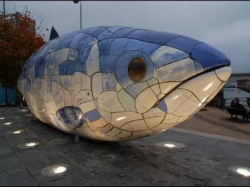 The Big Fish sculpture in Belfast lit by ground-level lights at night.