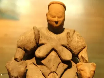 Seated Woman of Çatalhöyük sculpture showing a large woman seated on a throne with two feline heads beside her hands.