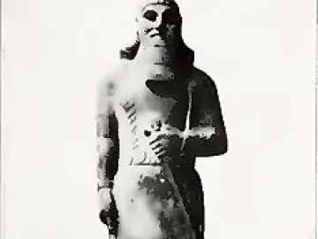 Statue of Ashurnasirpal II standing on a rectangular base, with a long carved garment and prominent beard.
