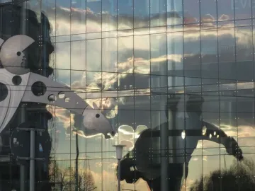 S-Printing Horse sculpture reflected in a glass building at sunset