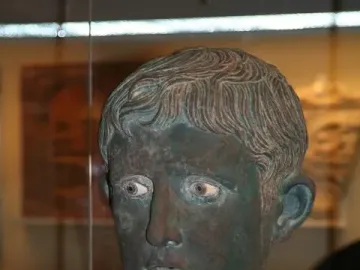 Meroë Head bronze sculpture with a weathered green patina and inlaid eyes.