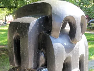 Treblinka abstract sculpture with blocky dark forms and carved openings in a paved outdoor setting.