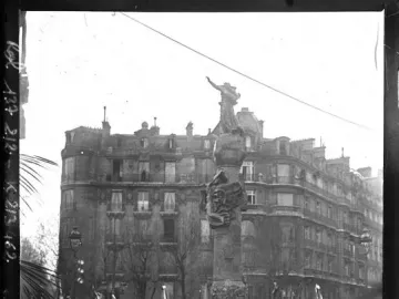 The Monument to Mickiewicz stands in a crowded Paris square during its inauguration, with a statue atop a decorated column and spectators in hats and umbrellas below.