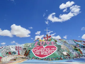 Salvation Mountain with colorful painted patterns, a red heart, the words “God Is Love,” and a white cross at the top.