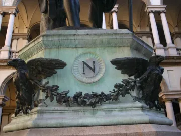 Bronze base of Napoleon as Mars the Peacemaker with two eagles and an N emblem, beneath the lower figure and in front of classical architecture.