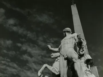 The Horse Tamers sculpture seen from behind, with a rearing horse and an obelisk rising in the background.