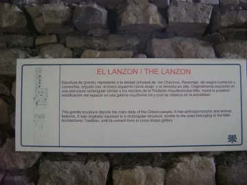 Informational sign about the Lanzón mounted on a rough stone wall, with a line drawing of the carved figure.