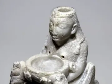 Lady of Galera figurine showing a seated stone figure holding a shallow bowl, flanked by two smaller winged figures.