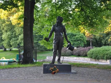 Pushkin statue in a park beside a body of water, with trees and paddle boats in the background.