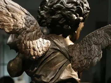 Back view of Putto with a Dolphin bronze sculpture, showing the winged figure, curled hair, drapery, and the dolphin’s tail.