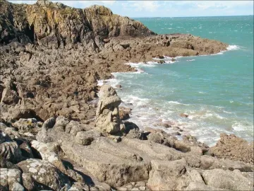 Rothéneuf Sculpted Rocks showing carved figures in granite along the rocky coast, with a prominent bust and reclining figure in the foreground.