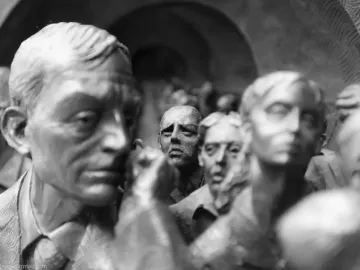 Close-up of bronze-like sculpted figures in The Meeting Place, including a man in a suit and tie in the foreground.