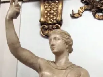 Marble statue of a wounded Amazon standing with one arm raised and a short tunic.