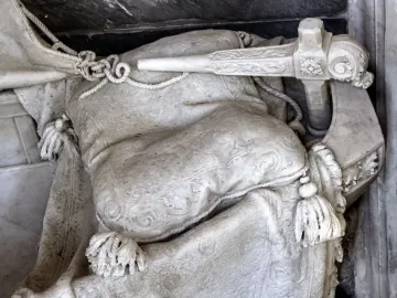 Close-up of Angelo Nocchiero showing carved draped stone fabric, ropes, tassels, and an ornate ship-like handle.