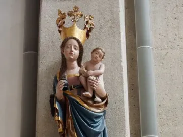 Inkpot Madonna statue of a crowned woman holding a child, with an inkpot and quill, mounted on a decorative bracket.