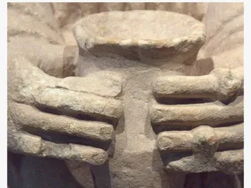 Close-up of the Lady of Cerro de los Santos showing carved hands holding a cylindrical vessel.