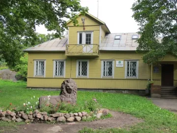 Recumbent lion statue in a flower bed beside a yellow building in Monrepos Park