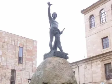 Monument to Viriato, a dark metal warrior sculpture on a large boulder behind an iron fence.