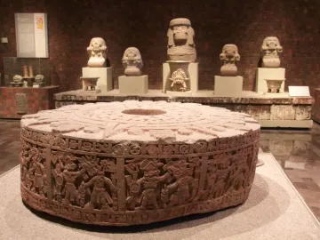 Stone of Motecuhzoma I with detailed carvings, circular frieze figures, and a central depression on top.
