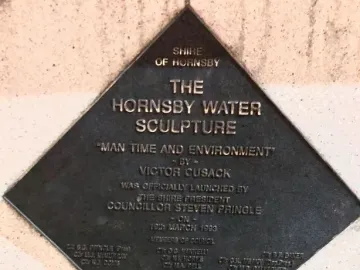 Bronze commemorative plaque for the Hornsby Water Sculpture mounted on a textured wall.