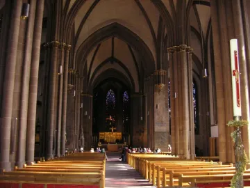 The Mindener Cross, a small golden crucifix, mounted on a tall white candle with a red stripe inside Minden Cathedral.