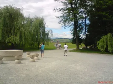 Table of Silence stone table with hourglass-shaped stools along a gravel path in a park
