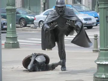 Vaartkapoen bronze sculpture showing a policeman being grabbed by a figure emerging from a manhole.