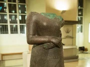Headless statue of Napir-Asu with hands clasped at the waist and an intricately decorated long garment.
