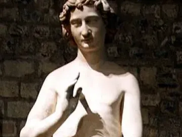 Adam statue with curly hair, one hand raised and the other holding leaves over his lower body.