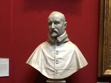 Bust of Carlo Antonio del Pozzo in white marble on a tiered pedestal against a red wall.