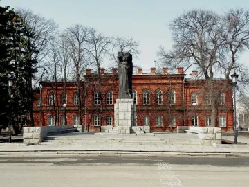 Karl Marx Monument standing in front of a long red brick building with arched windows.