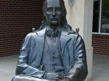 Wild Bill Hickok Memorial statue of a seated man with long hair, a mustache, and a bow tie