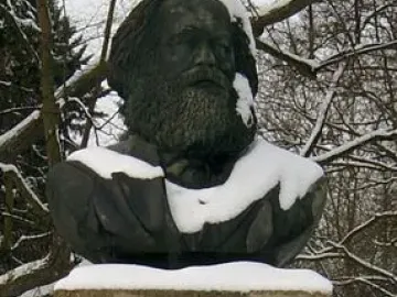 Karl Marx bust on a tall concrete pedestal in a snowy outdoor setting.