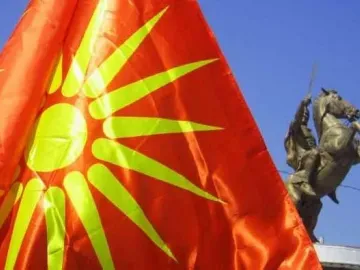 Bronze Warrior on Horseback statue partially visible beside a large red flag with a yellow sun emblem.