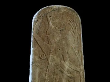 Stele of Baal with Thunderbolt, showing a horned deity raising a weapon above his head, with a small figure below and a plant-like emblem at the side.