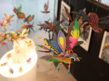 Brightly colored alebrije sculptures resembling insects and fantastical creatures hanging in a display.