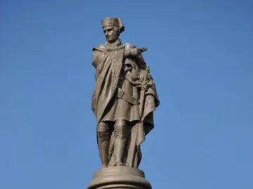Galceran Marquet statue atop an ornate column, with a robed figure holding a sword against a blue sky.