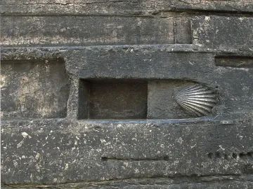 Scallop shell sculpture embedded in a dark gray wall relief at the Monument to Narcís Monturiol.
