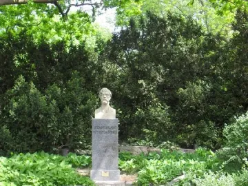 Bust of Stanisław Wyspiański on a tall stone pedestal in a garden