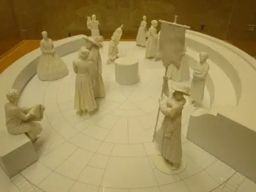 Virginia Women\'s Monument model showing a circular memorial with small statues and a figure holding a tall banner.